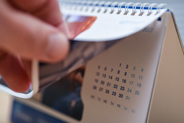Hand turns the page of the desk calendar