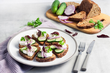 Canapes with toasted bread with sunflower and flax seeds, feta cheese, cucumber and onion