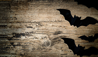 Big and small black bats on a wooden background with copy space 