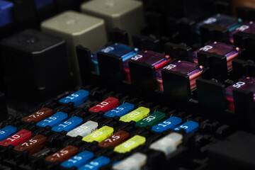 Automotive fuses on a black panel with holders and multi-colored markings - a protective device...