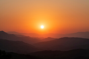 Fototapeta premium Bright summer sunset over the mountais silhouette. 