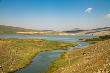 Beautiful landscape. Yellow hills mountains and small lake and river under blue sky.