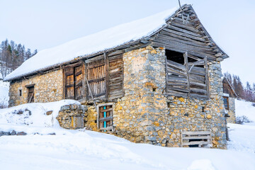 Winter evening landscape in french Alps. Old stone abandoned house on the mountain.