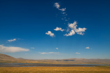 Beautiful landscape. Yellow hills mountains and small lake and blue sky.