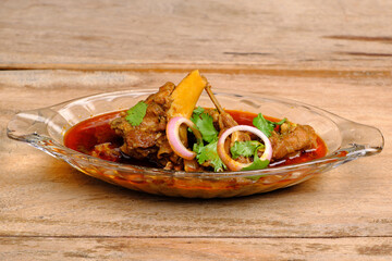 Mutton curry or meat dish in glass bowl on wooden background