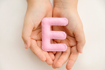 Stuffed felt letter of the alphabet in open hands of child. Kid holding handmade capital letter 