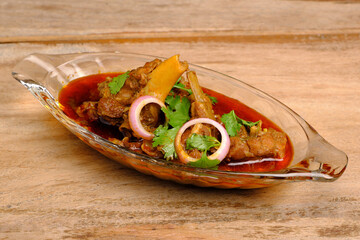 Mutton curry or meat dish in glass bowl on wooden background