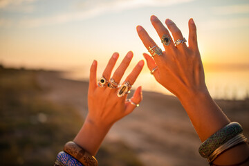 Female hands touch the sun. Hippie woman hands with silver rings at sunset. Indie boho vibes and bohemian style 