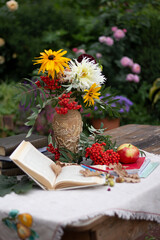 Autumn flowers with book and ashberry. Still-life with apple and flowers.