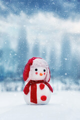 Toy snowman on a background of winter landscape during a snowfall. New Year and Christmas card