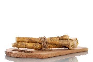 Several spicy horseradish roots on a wood board, close-up, isolated on white.