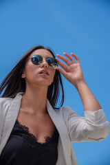 Close up image of happy brunette woman in sunglasses and summer clothes posing sideways outdoors