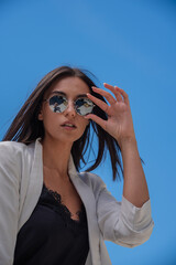 Close up image of happy brunette woman in sunglasses and summer clothes posing sideways outdoors