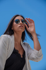 Close up image of happy brunette woman in sunglasses and summer clothes posing sideways outdoors