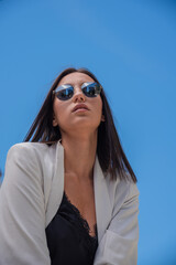 Close up image of happy brunette woman in sunglasses and summer clothes posing sideways outdoors