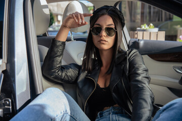Close up image of happy brunette woman in sunglasses and summer clothes posing sideways outdoors