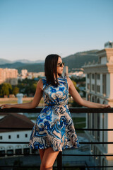 Close up image of happy brunette woman in sunglasses and summer clothes posing sideways outdoors