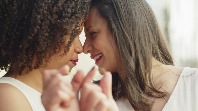 Close-up of kissing lesbian brides. Handheld shot of happy African-American women holding their wedding rings in front of camera. LGBT wedding ceremony, love concept