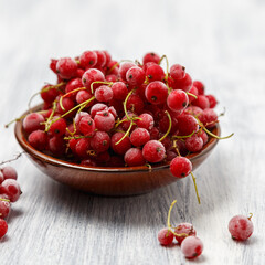 Frozen red currants in a brown ceramic vase on a white wooden table. Close-up.