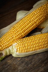 Fresh corn on the cob on a rustic wooden table, close up.