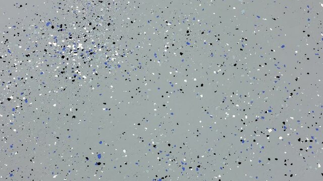 Panning down on the freshly painted garage floor with a gray epoxy finish sprinkled with blue, black and white plastic chips.