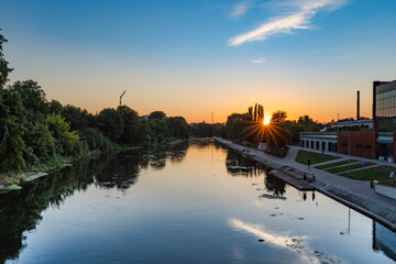 Sunset seen from the bridge in Bydgoszcz over the Brda River. - obrazy, fototapety, plakaty