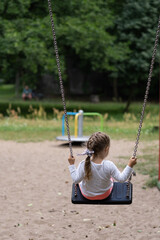 A girl swinging on a swing. - obrazy, fototapety, plakaty