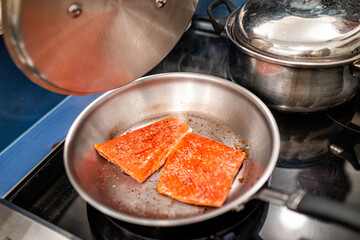 Raw sockeye salmon seafood fish with red color and omega 3 frying in skillet pan with lid on...
