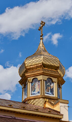 Fototapeta na wymiar Golden dome of the church. Background of blue sky and white clouds.