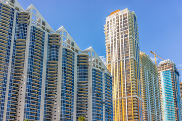 Sunny Isles Beach, USA apartment condo hotel building balconies during sunny day in Miami, Florida with skyscrapers and construction