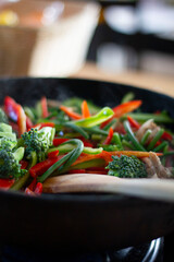Coocing vegetables in a frying pan. Broccoli, carrots, string beans on cast iron frying pan. Vegetarian Food.