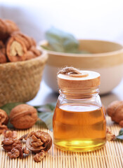 Bottle of golden color of walnut oils with its kernel and shell in background. Consuming walnut oil may improve heart health, lower blood sugar, and have anticancer effects 