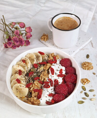 A bowl of oat meal porridge with fruits and whole grains such as walnuts,koji berry, chia, pumpkin and sunflower seed with a cup of coffee, healthy breakfast concept 