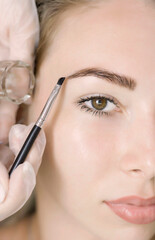 Young woman correcting eyebrow shape with brush, closeup