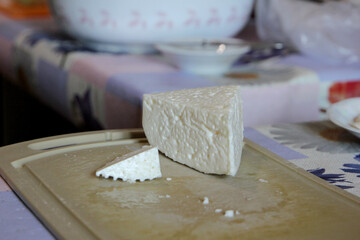 A piece of Ossetian salted hard cheese on a wooden board