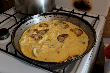 Cooked omelet with fried zucchini in a frying pan