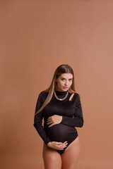 Obraz premium Beautiful pregnant young woman in studio on beige background