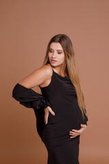 Beautiful pregnant young woman in studio on beige background