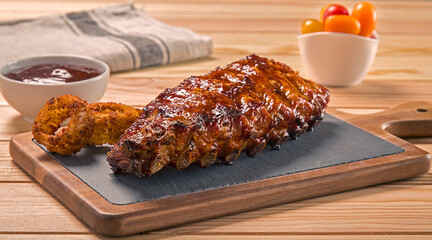 costillas de cerdo a la brasa con salsa barbacoa, aros de cebolla y tomatitos