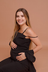 Beautiful pregnant young woman in studio on beige background