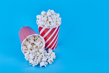 Two glasses full of popcorn on a blue background