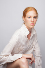 Portrait of a young woman with exquisite makeup in a linen shirt with long sleeves. Artistic studio...