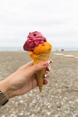 Ice cream in a waffle cup in the hand of a girl on the beach of Batumi