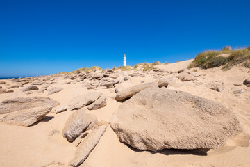 beach with rocks and big stones in Trafalgar Cape Natural Park with lighthouse, next to Canos Meca...
