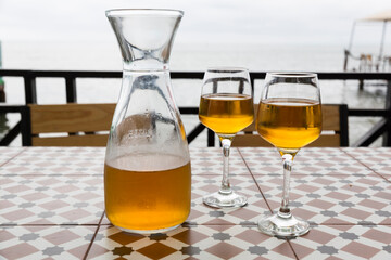 Orange wine from Kvevri. Batumi, Tbilisi restaurant on the seashore. A pitcher and two glasses....