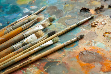Tubes of oil paint, palette and artist paintbrushes closeup.