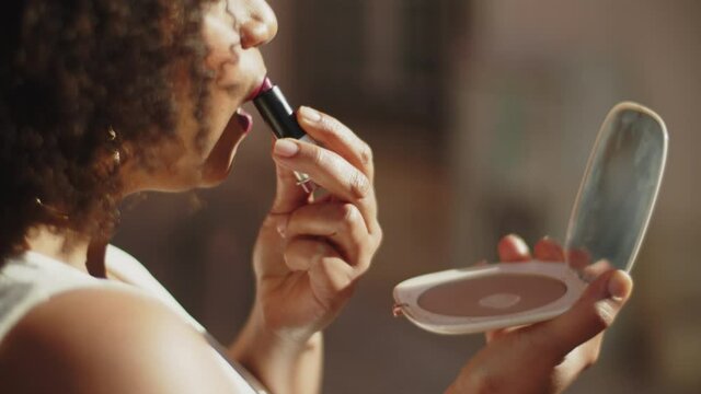 Close-up of bride painting lips and looking in mirror. Handheld shot African-American woman preparing for major event in her life, getting ready for wedding ceremony. Party, make up, beauty concept