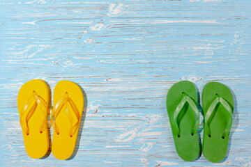 yellow and chewed flip flops on a wooden background, view from above, place under the text
