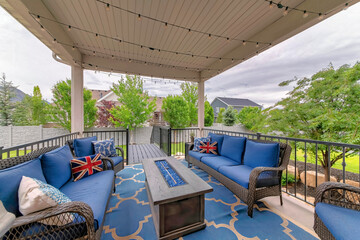 Cozy outdoor deck with fire pit table and woven sofas with blue cushions