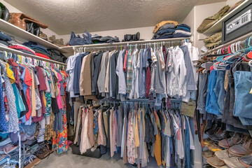 Full walk in closet with clothes hanging on the clothing rods